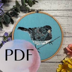 May include: A blue and white embroidery hoop with a black and white bird design. The bird is perched on a branch and has a detailed pattern of flowers and leaves. The hoop is surrounded by a white background.