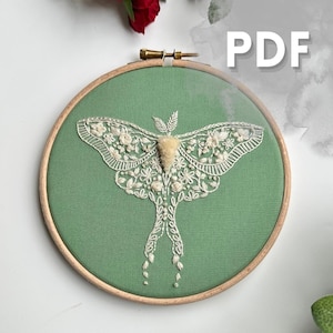 May include: A detailed embroidered moth design in a wooden hoop. The moth is white with floral patterns, set against a green fabric. The word "PDF" is visible in the upper right corner.