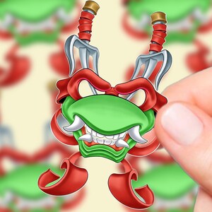 May include: A cartoon sticker featuring a green face with white fangs, red accents, and two silver swords. The sticker is held by a hand against a blurred background of similar stickers.