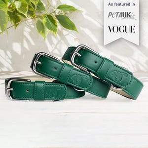 Pode incluir: Três coleiras de cão de couro verde com fivelas prateadas. Cada coleira tem uma pequena silhueta de cão em relevo no couro. As coleiras estão empilhadas umas sobre as outras. O texto "As featured in PetAUK VOGUE" é visível no fundo.