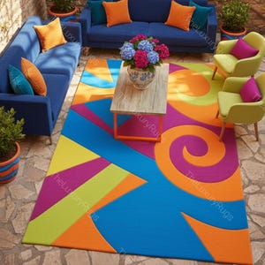 Op de afbeelding: Een kleurrijk geometrisch tapijt met een levendig ontwerp met blauwe, oranje, paarse en groene vormen. Het tapijt staat in een buitenomgeving met blauwe banken, gele stoelen en een houten salontafel.