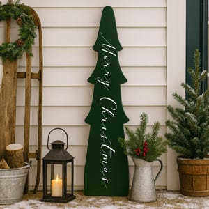 Timeless porch leaner evergreen tree elegantly hand painted with Merry Christmas. Outdoor Christmas decor & wooden winter porch decorations.