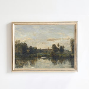 May include: A framed landscape painting depicting a river scene with trees and a cloudy sky. The painting is in a gold frame and has a rustic, vintage feel.