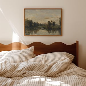 May include: A wooden bed frame with a wavy headboard and a white and gray striped duvet cover. A framed painting of a landscape with a river and trees hangs on the wall above the bed.