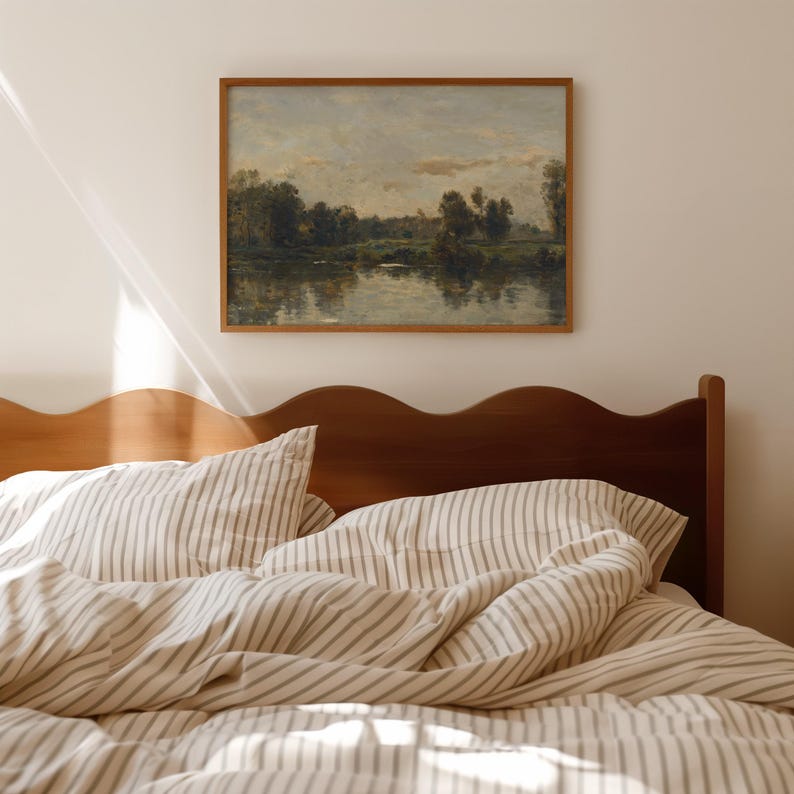 May include: A wooden bed frame with a wavy headboard and a white and gray striped duvet cover. A framed painting of a landscape with a river and trees hangs on the wall above the bed.