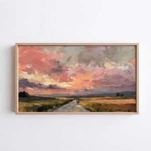 Puede incluir: Pintura al óleo de una puesta de sol sobre un paisaje rural. El cielo está lleno de nubes rosas, naranjas y moradas. Un camino atraviesa un campo de color amarillo y verde. La obra de arte está enmarcada en un marco de madera clara.