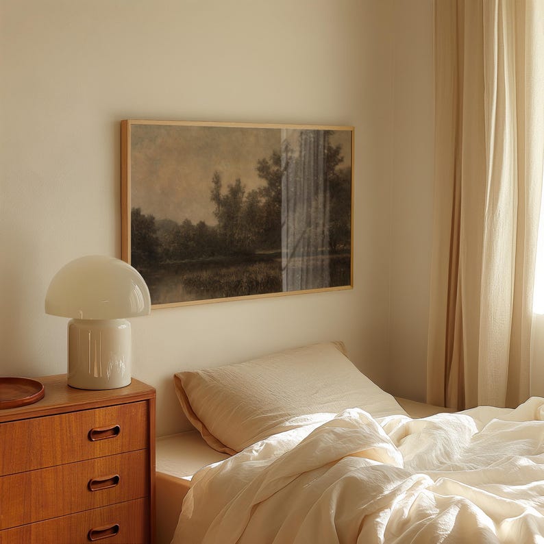 Pu&ograve; includere: Una lampada da comodino bianca con un paralume a forma di fungo si trova su una cassettiera in legno accanto a un letto con biancheria da letto in lino bianco. Un dipinto di paesaggio incorniciato &egrave; appeso al muro sopra la cassettiera.