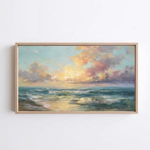 May include: A framed landscape painting depicts a seascape with a vibrant sunset. The sky is filled with peach, pink, and yellow clouds. The ocean waves are a mix of teal and white, with a golden reflection of the sun.