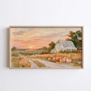 May include: A rectangular framed painting depicting a rural landscape at sunset with a white barn, a dirt path, and several orange pumpkins in the foreground. The sky is filled with soft pink and orange clouds above a field of dry grass and trees.