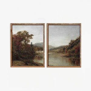 May include: Two framed landscape paintings depicting a river scene with trees and mountains in the background. The paintings are in a rustic wooden frame.