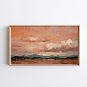 Puede incluir: Pintura de paisaje abstracto en un marco de madera clara. La obra representa una puesta de sol con tonos naranja y rosa en el cielo, nubes blancas y una cordillera verde oscuro en la distancia.