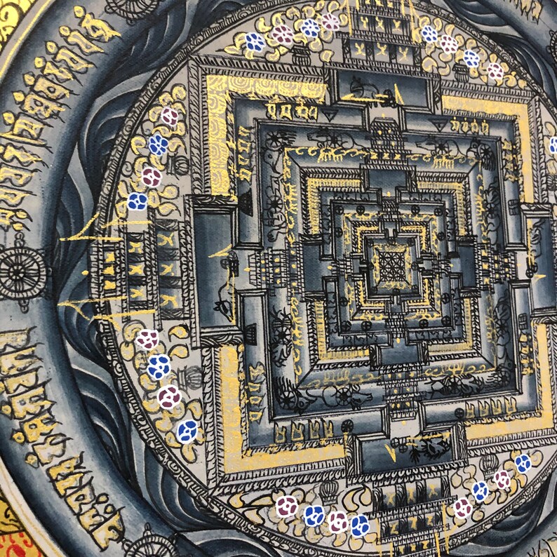 Puede incluir: Un mandala con un dise&ntilde;o cuadrado en el centro, rodeado de un c&iacute;rculo de patrones intrincados. El mandala est&aacute; pintado en tonos grises y dorados, con peque&ntilde;as flores azules y rojas alrededor del borde exterior.