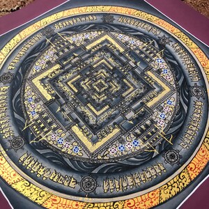 Puede incluir: Un mandala negro y dorado con intrincados detalles y un patr&oacute;n cuadrado en el centro. El mandala est&aacute; rodeado por un borde circular con texto en un idioma extranjero.
