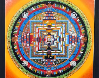 May include: A vibrant, detailed mandala painting with a square central design and concentric circular patterns. The artwork features a rich palette of colors including orange, blue, red, and green, with intricate figures and symbols. The painting is set against a black background.