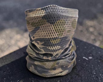 May include: A camouflage-patterned neck gaiter made of a breathable, perforated fabric. The gaiter features a mix of green, brown, and gray tones in a military-style design. The fabric appears lightweight and suitable for outdoor activities.