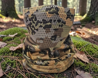 May include: A camouflage-patterned neck gaiter, featuring a mesh design. The color palette includes shades of brown, green, and black, creating a woodland camouflage effect. The gaiter is designed to be worn around the neck and lower face.
