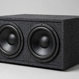 May include: A rectangular subwoofer enclosure featuring two large black circular speakers mounted side-by-side on the front panel. The entire exterior of the box is covered in a dark grey, textured carpet-like material with a solid, sturdy build.