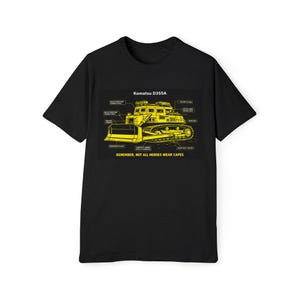 May include: Black t-shirt featuring a yellow diagram of a Komatsu D355A bulldozer with labeled parts. The text "Komatsu D355A" is at the top, and "REMEMBER, NOT ALL HEROES WEAR CAPES" is at the bottom.