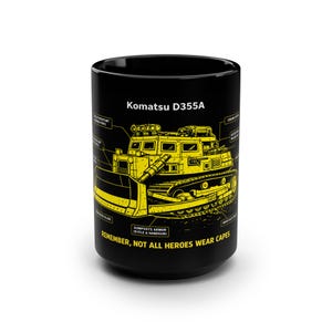 May include: Black ceramic mug with a yellow diagram of a Komatsu D355A bulldozer. The mug has the text "Komatsu D355A" and "REMEMBER, NOT ALL HEROES WEAR CAPES" printed on it.