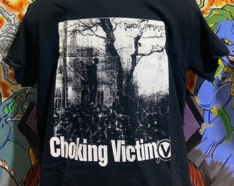 May include: Black t-shirt with a white graphic print of a tree and a house. The text "Squatting Paradise" and "Choking Victim" are printed on the shirt.