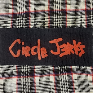 May include: A black patch with the words "Circle Jerks" written in red.