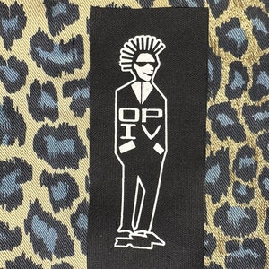 May include: Black and white iron-on patch featuring a cartoon figure with a mohawk hairstyle wearing a suit and sunglasses. The text "OP IV" is printed on the patch.