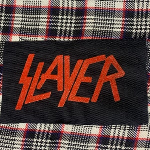 May include: Black fabric patch with the word "SLAYER" in red glitter lettering.
