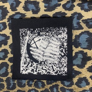 May include: Black and white patch with the text "Destroy Society" and a graphic of a crossed-out axe. The patch is sewn onto a leopard print fabric.