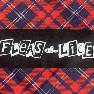 May include: Black rectangular patch with the words "Fleas and Lice" in white, stylized text. The patch is set against a red, navy blue, and white plaid background. The patch is likely for clothing or accessories.