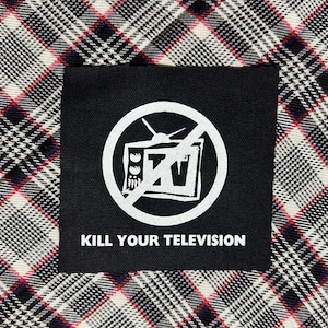 May include: Black square patch with a white graphic of a television crossed out inside a circle. The text "KILL YOUR TELEVISION" is below the graphic. The patch is on a black, white, and red plaid fabric.
