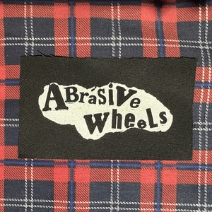 May include: Black fabric patch with white lettering that reads "Abrasive Wheels".