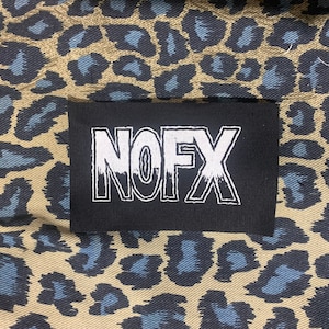 May include: Black and white embroidered patch with the word "NOFX" in a stylized font.