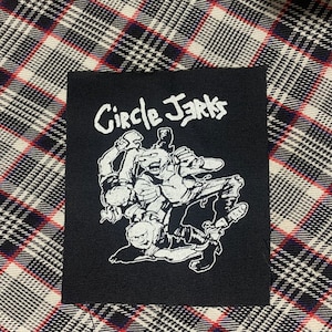 May include: Black and white embroidered patch with the text "Circle Jerks" and a graphic of three figures wrestling.