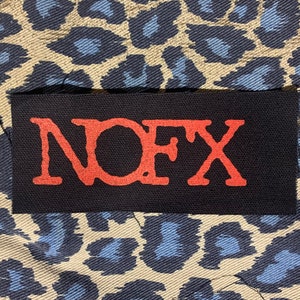 May include: A black fabric patch with the word "NOFX" in red lettering.