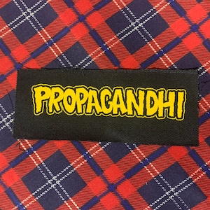 May include: Black fabric patch with the word "PROPAGANDHI" in yellow lettering.