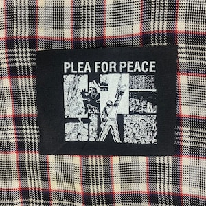 May include: Black patch with white text that reads "PLEA FOR PEACE" and a graphic image of people protesting.