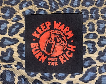 May include: A black patch with red text that reads "Keep Warm. Burn Out The Rich."  The text is in a circle with a red hand holding a spray bottle inside the circle.