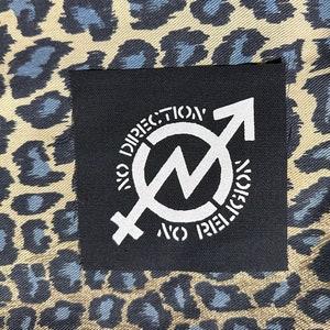 May include: Black patch with white text and a symbol. The text reads "No Direction No Religion" and the symbol is a circle with a lightning bolt inside and a male and female symbol on either side.
