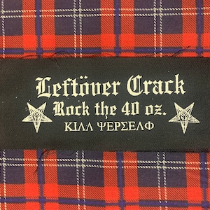 May include: Black patch with white text that reads "Leftover Crack Rock the 40 oz. KILLA CERVEZA" with two white pentagrams on either side.