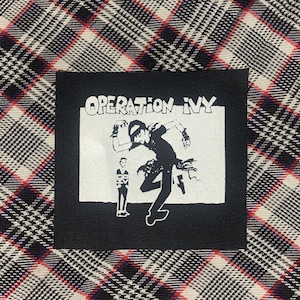 May include: Black and white iron-on patch with the text "OPERATION IVY" and a graphic of two figures in a punk rock style.