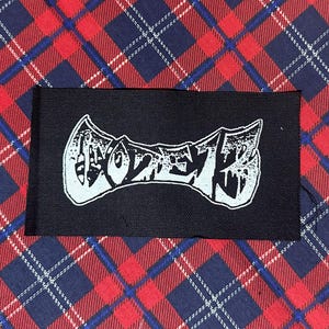 May include: A black rectangular patch with the white word "DOZER" in a stylized font. The patch is set against a red, blue, and white plaid fabric background.