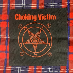 May include: Black square patch with the words "Choking Victim" in red, above a red pentagram with a goat's head inside a circle. The patch is set against a red, blue, and white plaid background.
