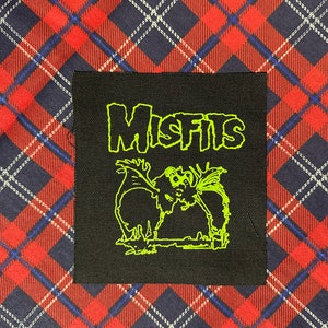 May include: Black and green embroidered patch with the word "Misfits" in a stylized font and a green bat with a skull-like face.