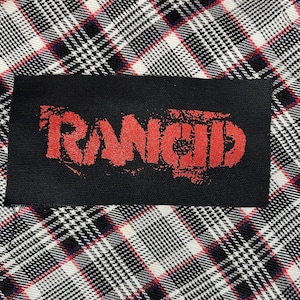 May include: Black fabric patch with the word "RANCID" printed in red.