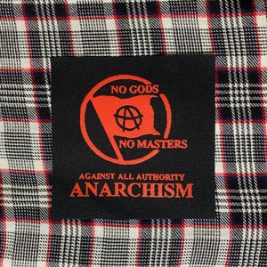 May include: Black patch with red text and a red circle containing an anarchy symbol and the words "No Gods No Masters". The text "Against All Authority Anarchism" is below the circle.