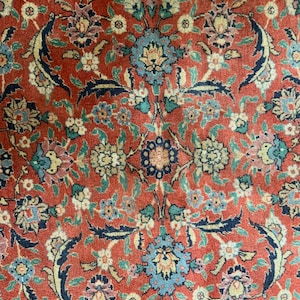 May include: A red rug with a floral pattern. The rug has a traditional Persian design with intricate details and a variety of colors, including blue, green, and cream.