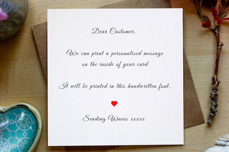 May include: A white card with black text that reads "Dear Customer, We can print a personalised message on the inside of your card. It will be printed in this handwritten font. Sending Waves xxxxx". A red heart is printed below the text.