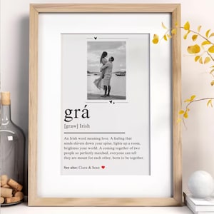 May include: Framed print with a black and white photo of a couple. The print features the Irish word "grá" meaning love, with a definition below. The frame is light wood, and the print is on white paper.