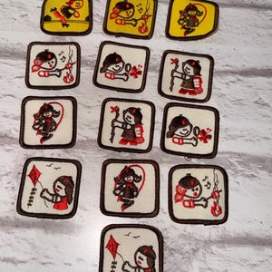 May include: A selection of embroidered patches with a brown border, showcasing a cartoon girl engaged in outdoor pursuits. The patches depict activities such as playing a musical instrument, archery, and flying a kite. The backgrounds are either yellow or white.