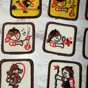 May include: A selection of embroidered patches with cartoon figures engaged in different activities. The patches are square with a brown border. The figures are in brown, red, and black, set against yellow or white backgrounds.